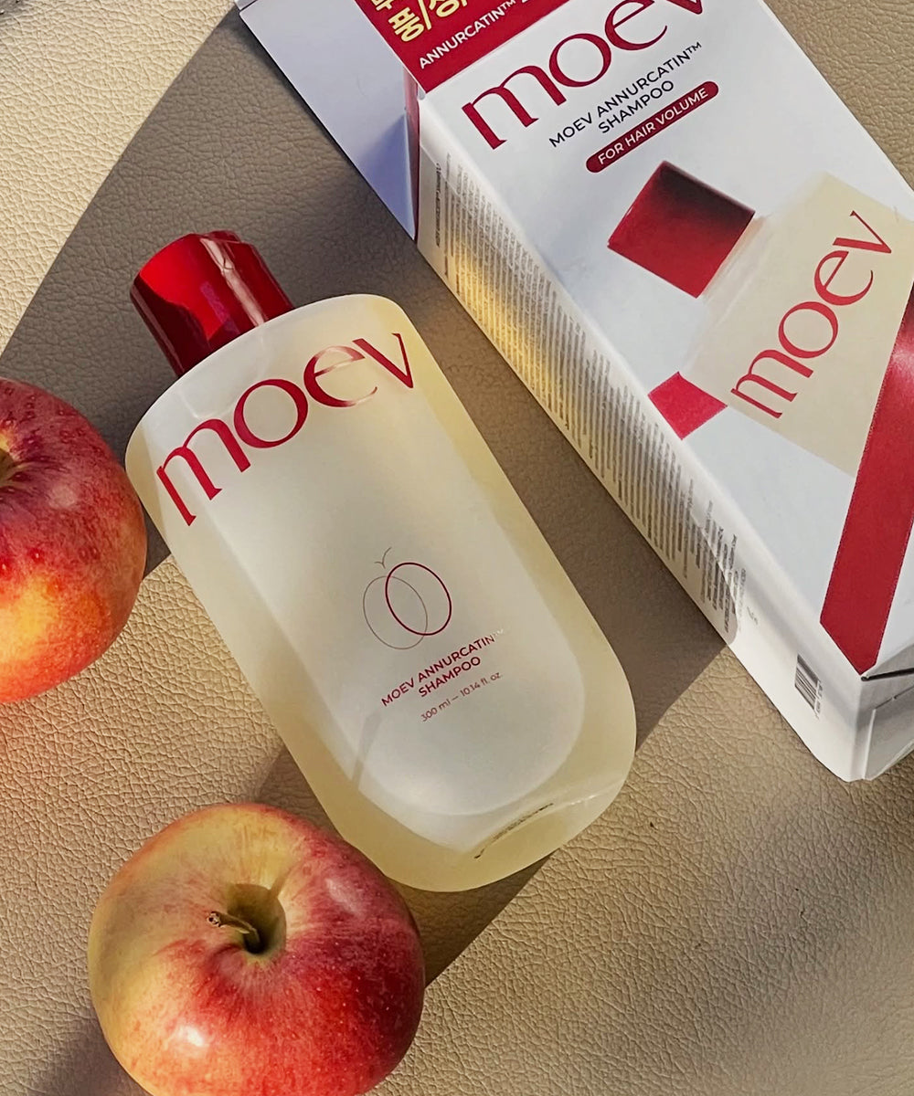 Moev shampoo bottle and box with apples on a beige surface