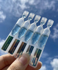 A hand using the glass dropper to dispense the Numbuzin Blue Bio-Retinol Serum, highlighting its lightweight, translucent blue liquid texture designed for quick absorption