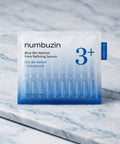 Macro view of a single drop of the Numbuzin Blue Bio-Retinol serum on a clean surface, showcasing its glossy, high-absorption consistency and unique natural blue tint