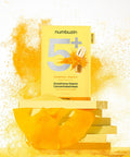 Close-up of the Numbuzin No.5 sheet mask being removed from the packaging, showcasing the yellow-tinted essence infused with concentrated glutathione and Vitamin C