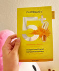 A lifestyle shot of the Numbuzin No.5 Vitamin Mask resting on a clean, reflective surface, emphasizing the professional-grade brightening treatment for dull skin