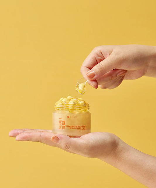 Hand holding a jar of skincare product with a yellow background