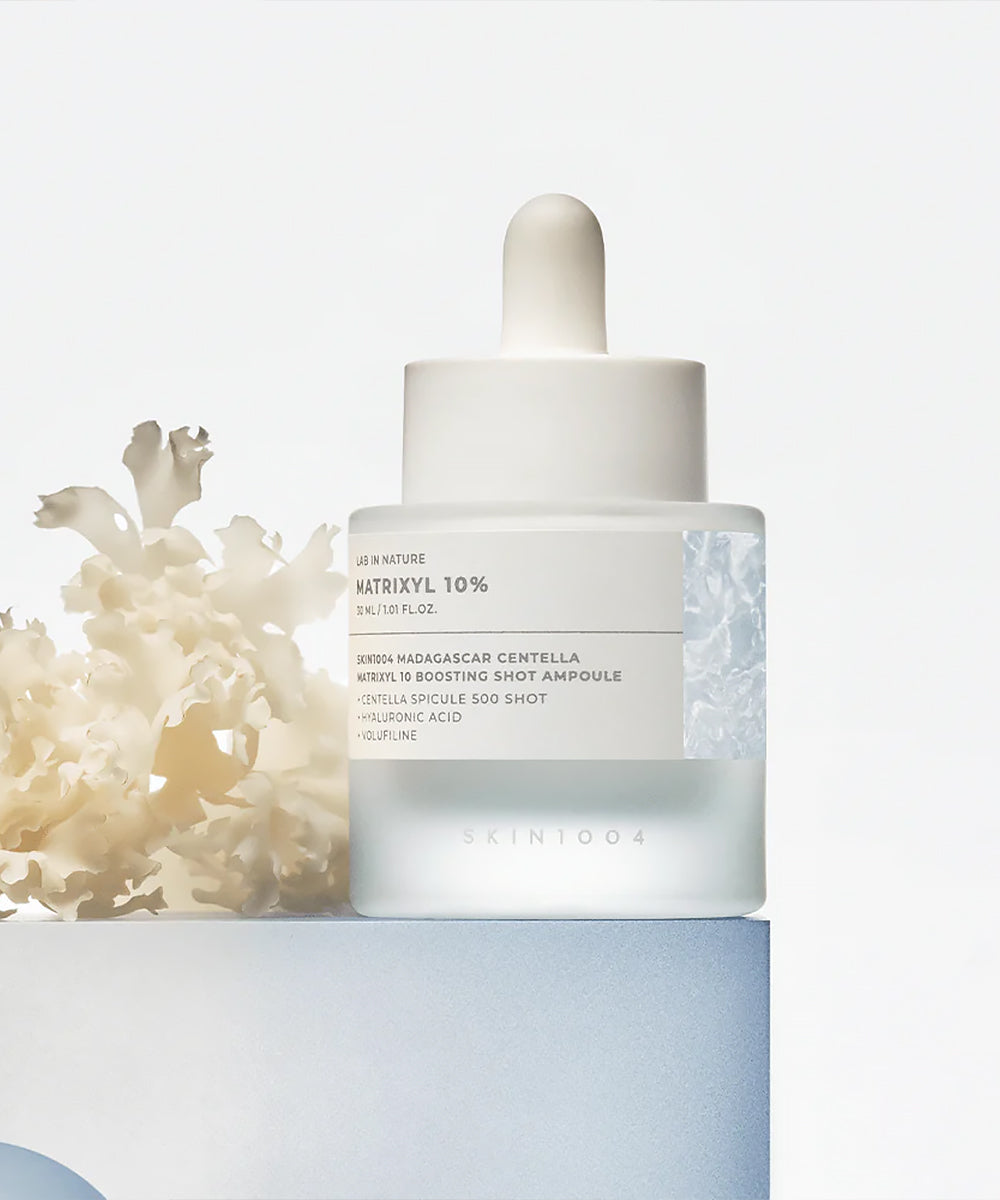 Skincare dropper bottle with coral on a light background