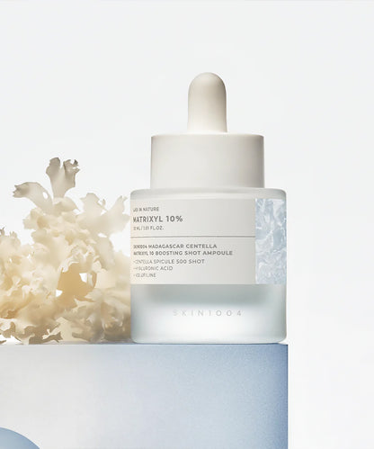 Skincare dropper bottle with coral on a light background