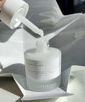 Skincare serum bottle with dropper on a reflective surface