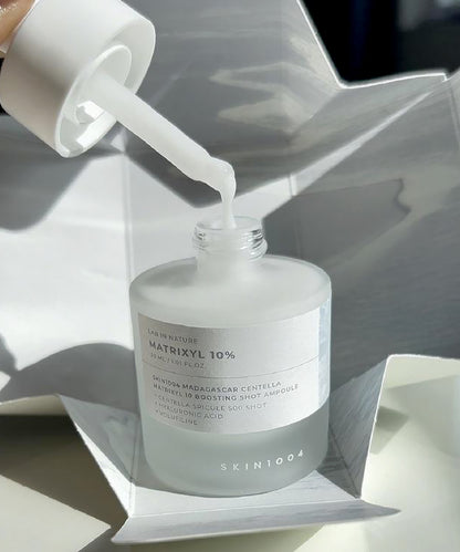 Skincare serum bottle with dropper on a reflective surface