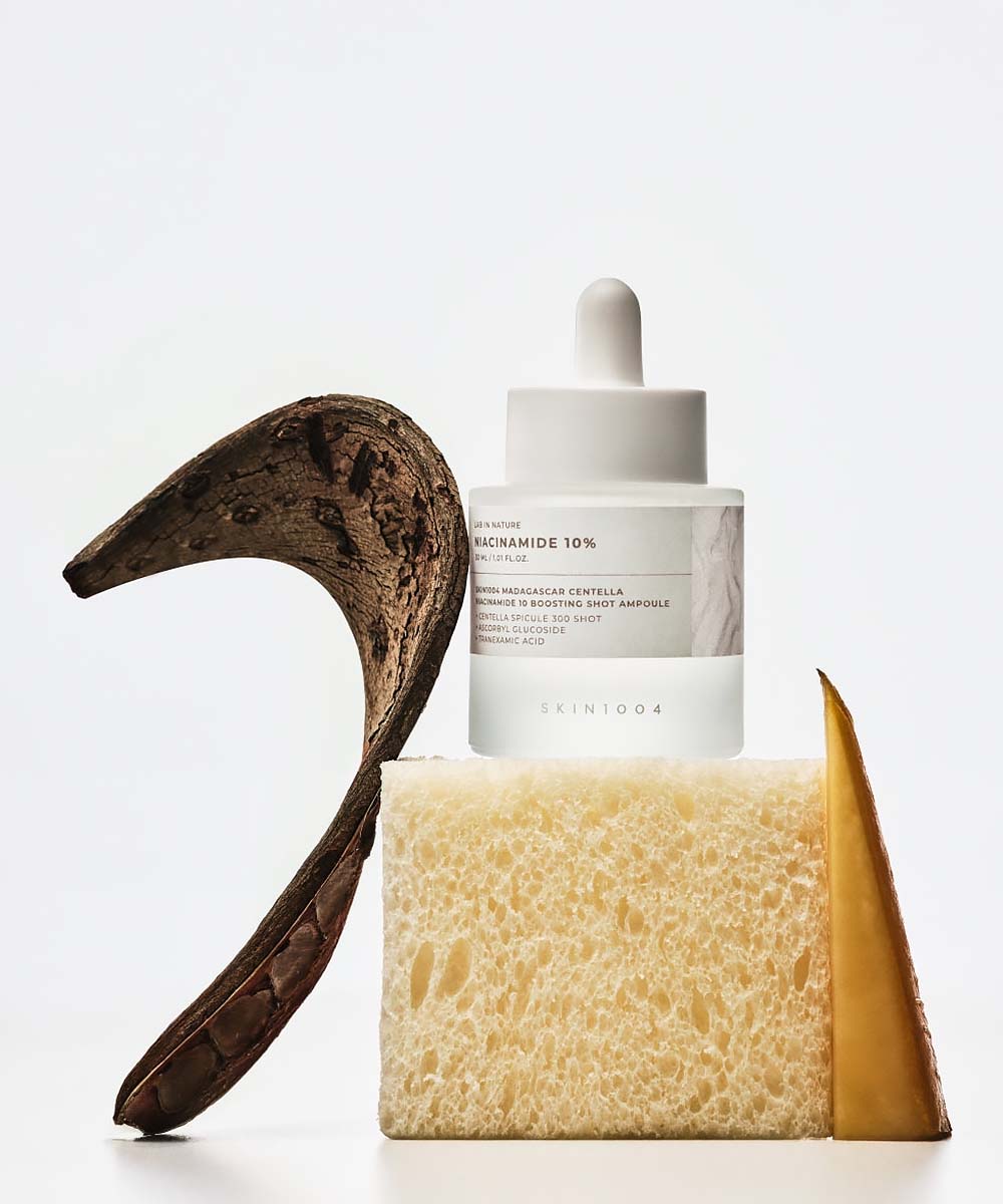 Skincare bottle with a wooden hook and sponge on a white background
