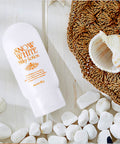 Snow White Milky Lotion bottle on a wooden surface with pebbles and a shell.