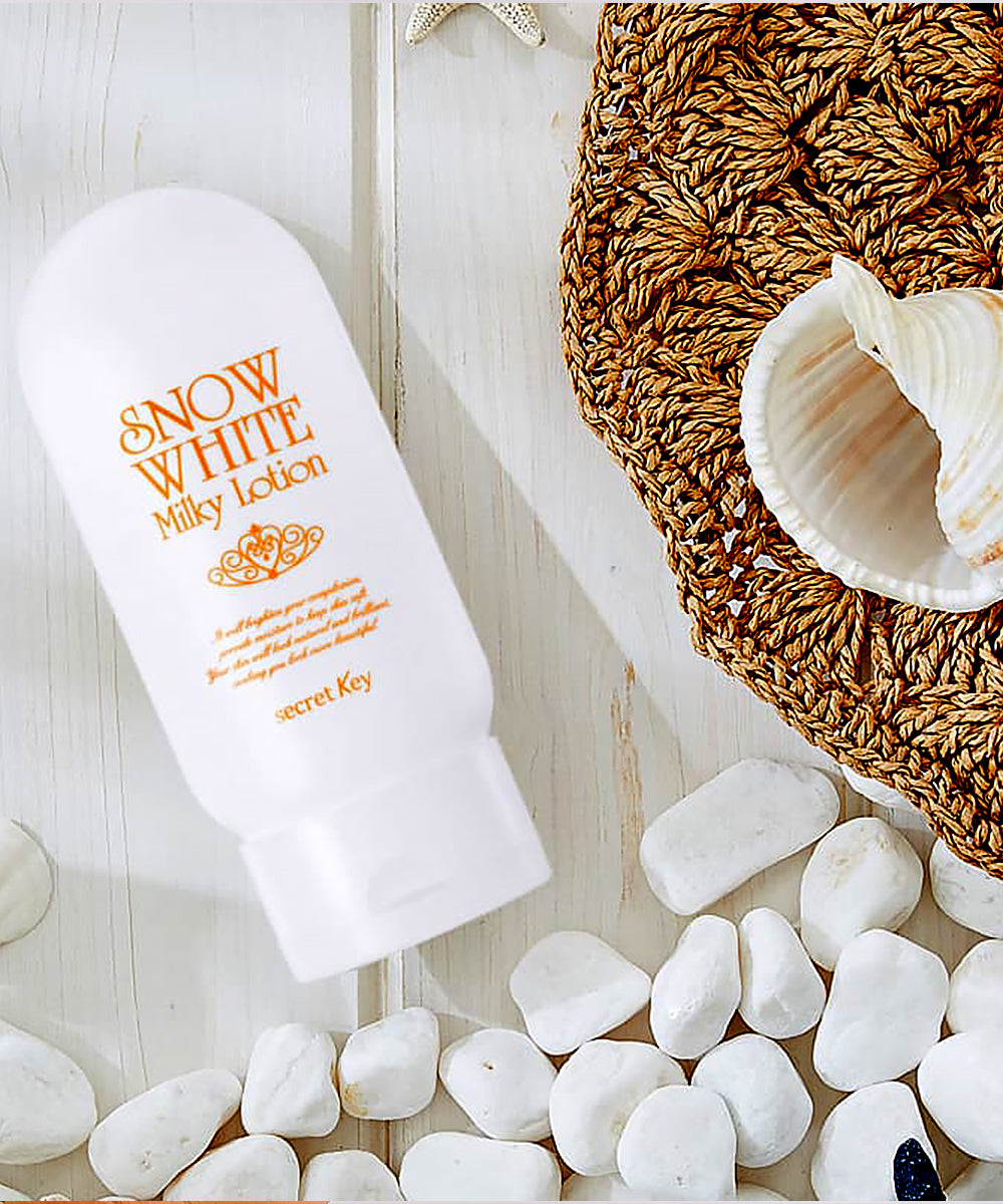 Snow White Milky Lotion bottle on a wooden surface with pebbles and a shell.