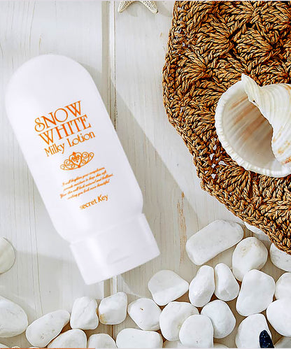 Snow White Milky Lotion bottle on a wooden surface with pebbles and a shell.