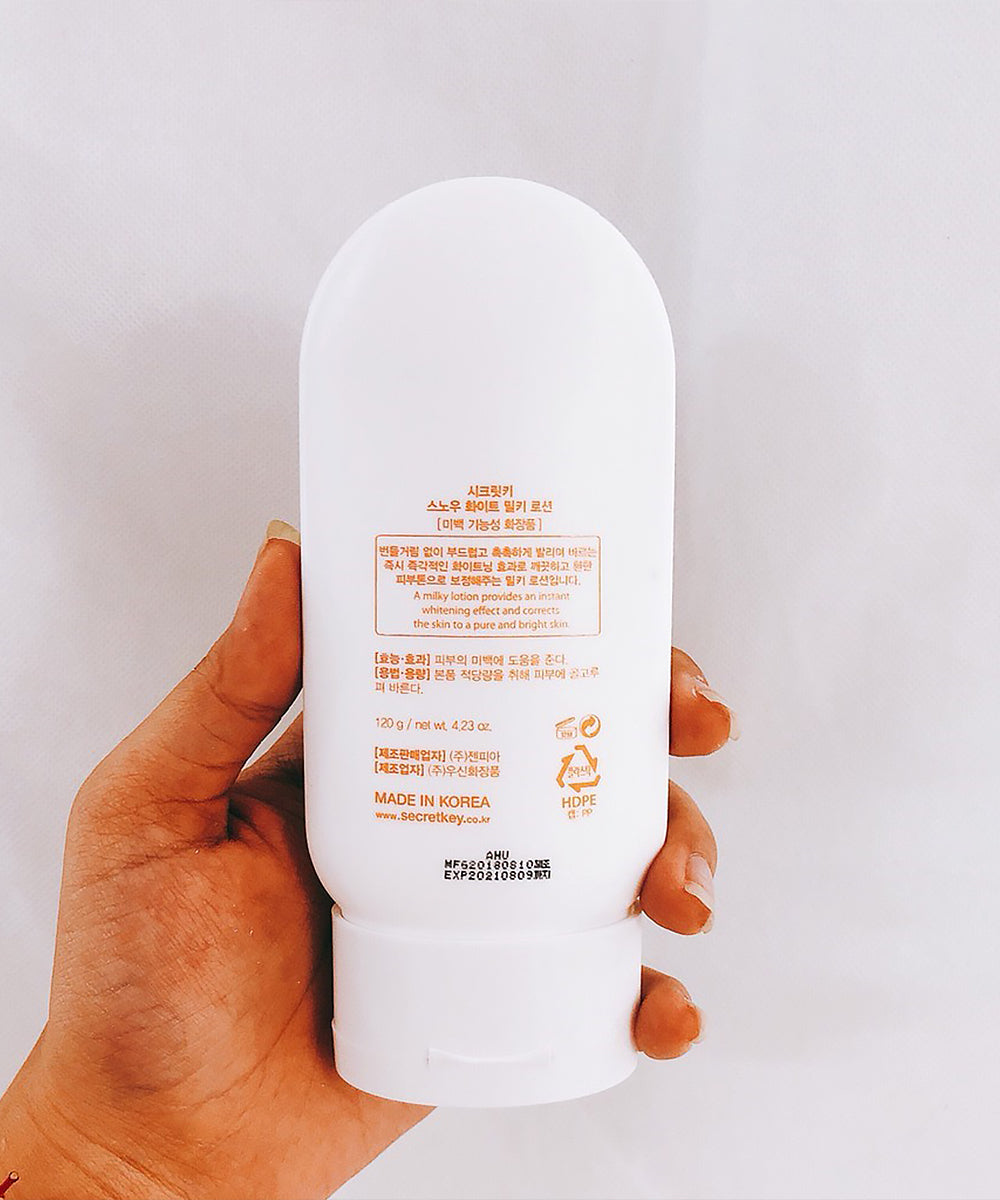 Hand holding a white bottle with text on a light gray background