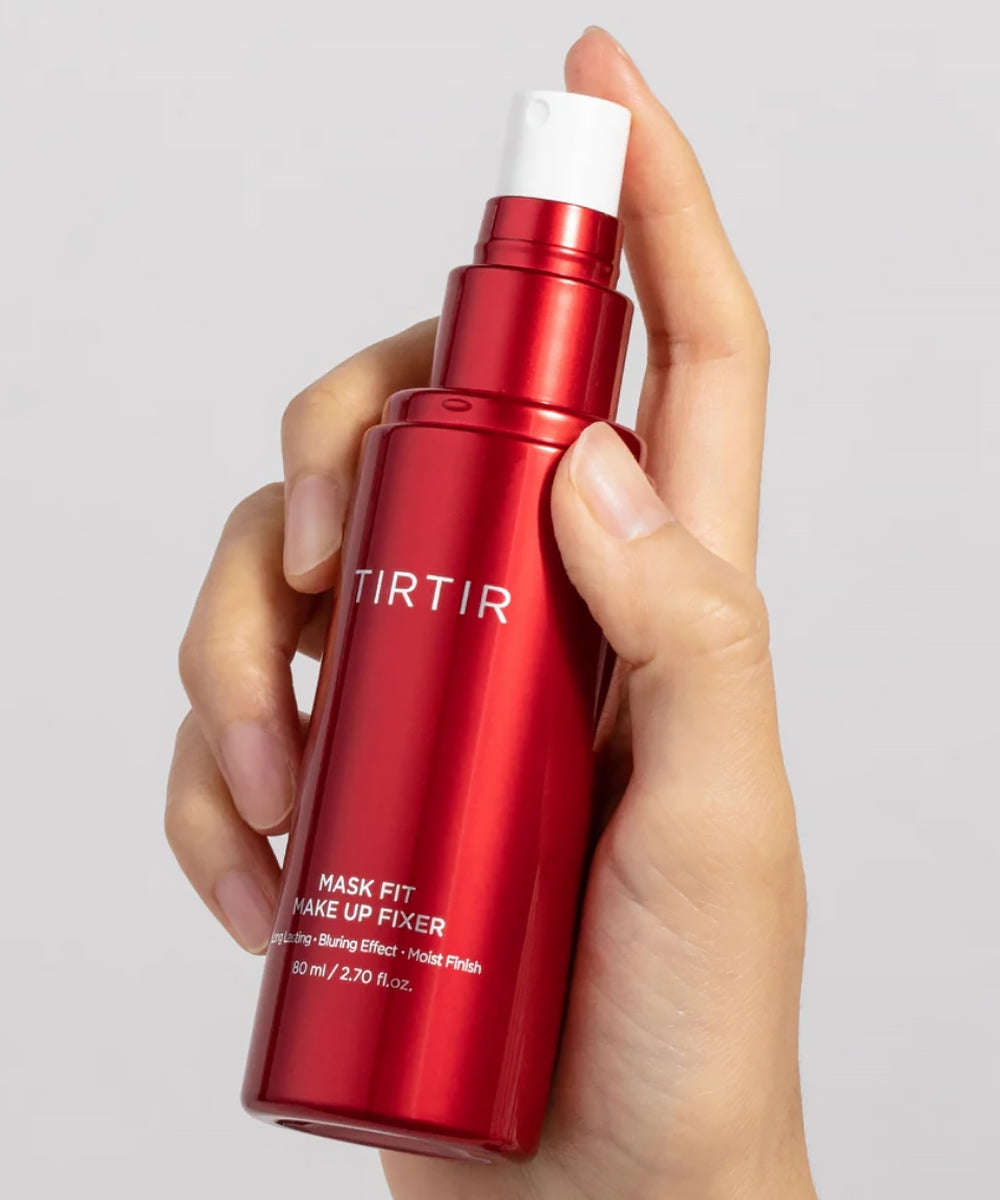 Red TIRTIR skincare bottle held in a hand against a gray background