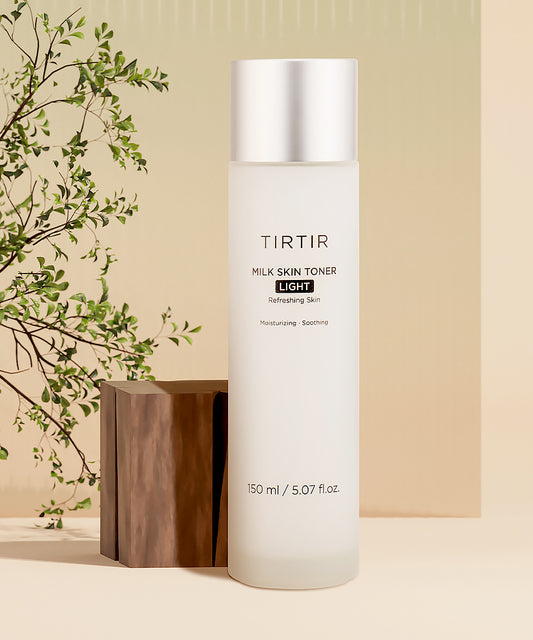 TIRTIR milk skin toner bottle on a beige background with a wooden block and green leaves.
