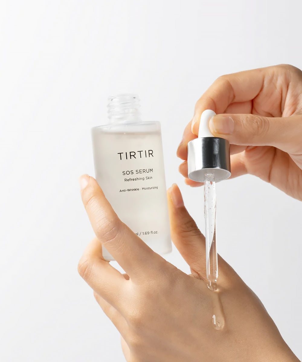 Close-up of TIRTIR SOS Serum being dispensed from a glass dropper onto a hand, highlighting its clear, viscous, and moisturizing texture