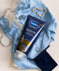 Vaseline Gluta-Liya tube on a blue fabric background with jewelry and a map.
