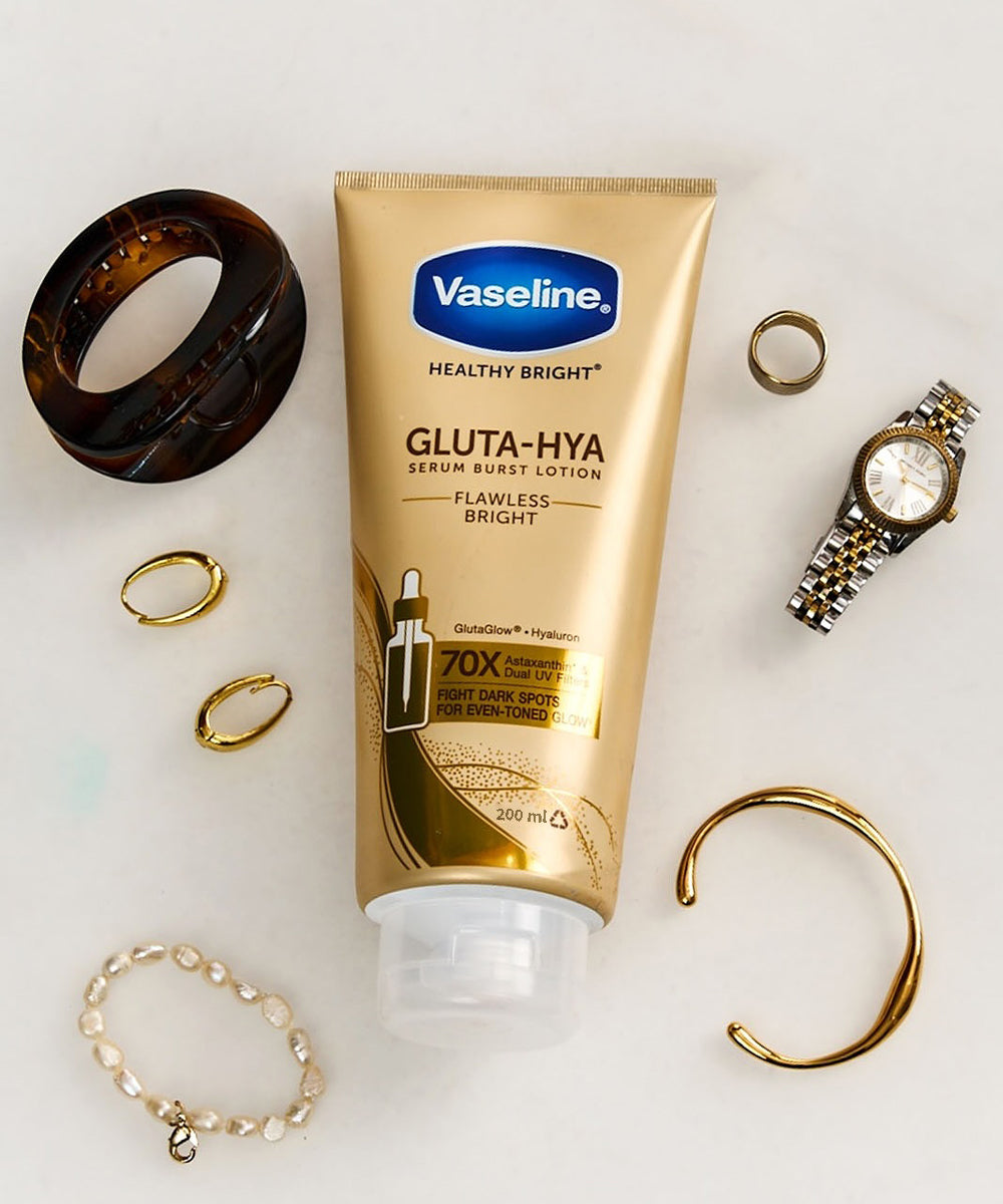 Vaseline Gluta-Hya lotion tube surrounded by jewelry on a light background