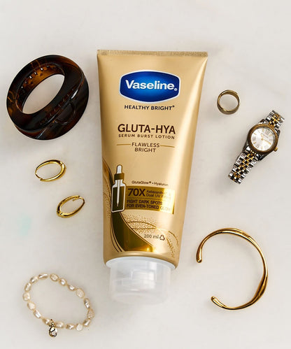 Vaseline Gluta-Hya lotion tube surrounded by jewelry on a light background
