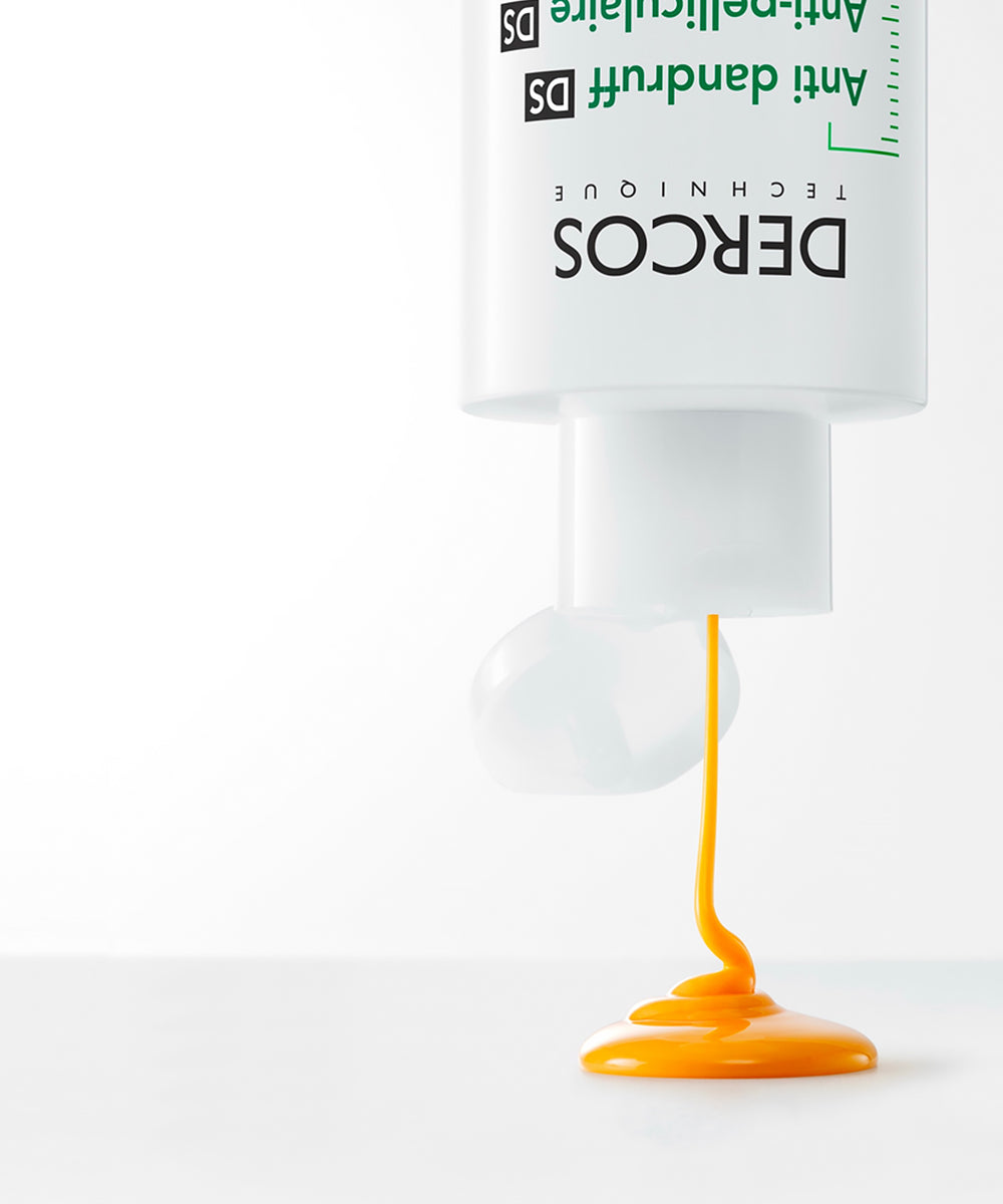 DERCOS hair care product with yellow substance spilling out on a white background