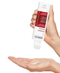Hand holding a tube of DERDOC skincare product with visible cream on the palm against a white background