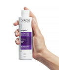 Manicured hand holding Vichy Dercos Neogenic Redensifying Shampoo bottle, showing product detail